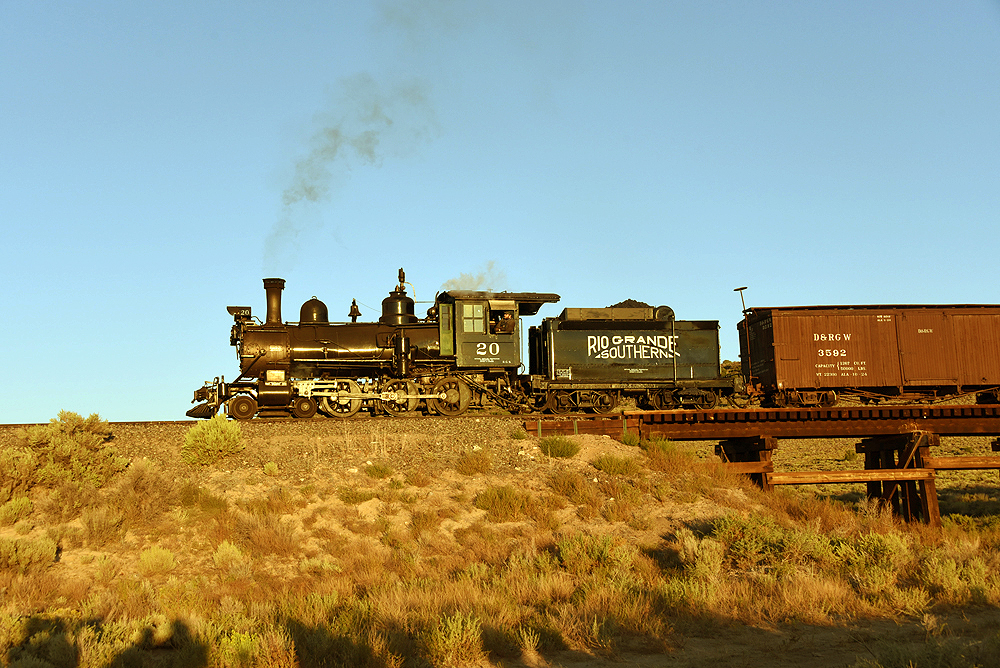 Small steam locomotive with freight car in a high plains landscape