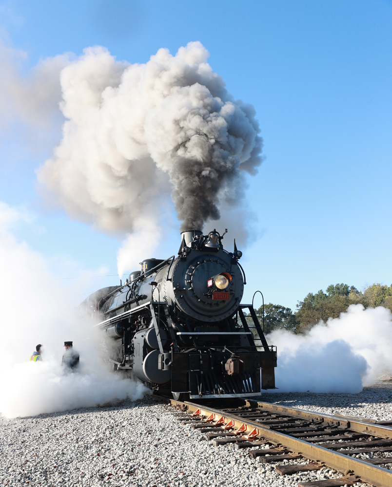 Steam locomotive exhausts steam near the ground