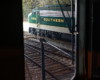 Green and white streamlined diesel as viewed through cab window of another locomotive