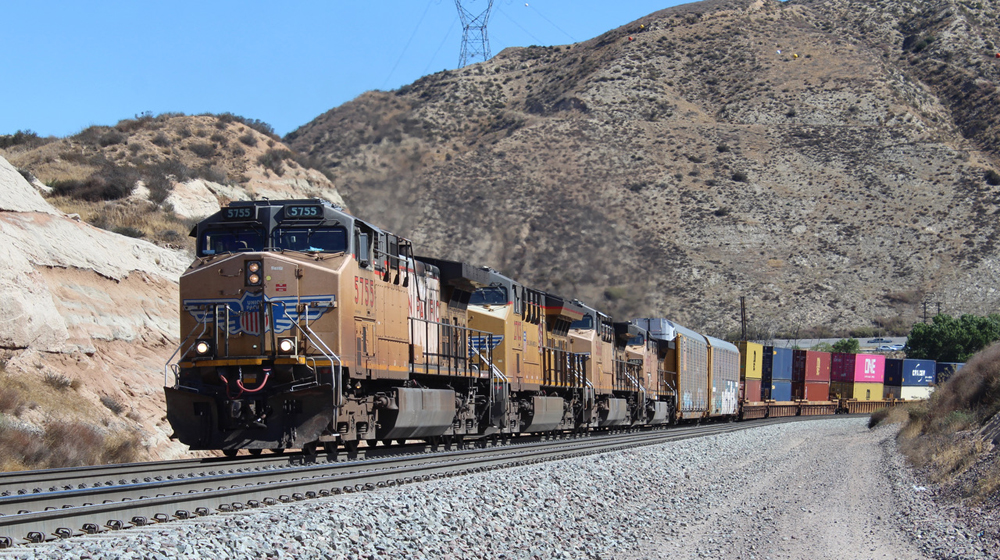 Four yellow locomotives on train climbing hill