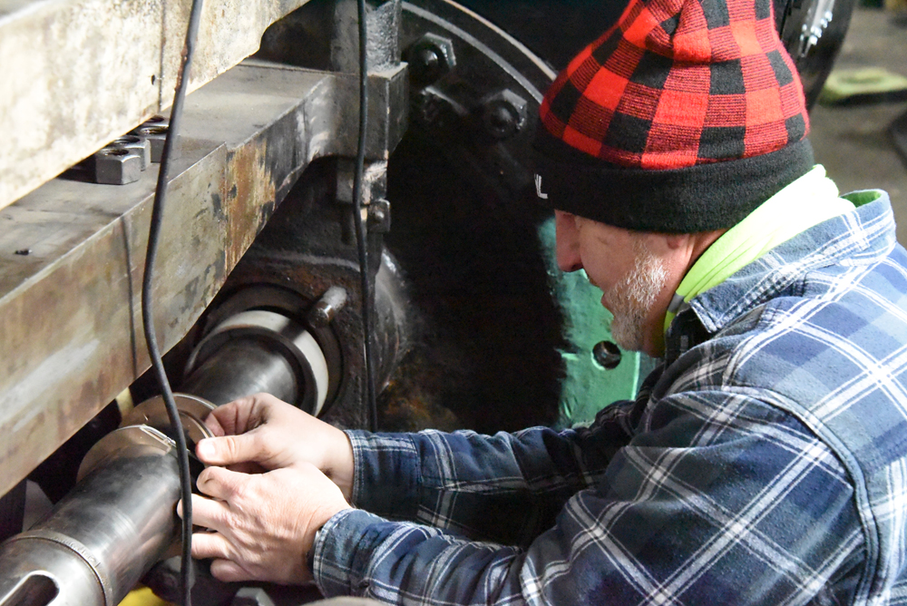 Man dressed for cold weather working on steam locomotive