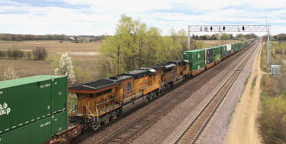 Yellow locomotives in with double-stack cars ahead and behind