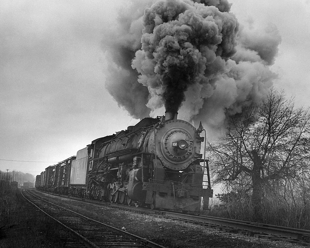Smoking steam locomotive leads freight train.