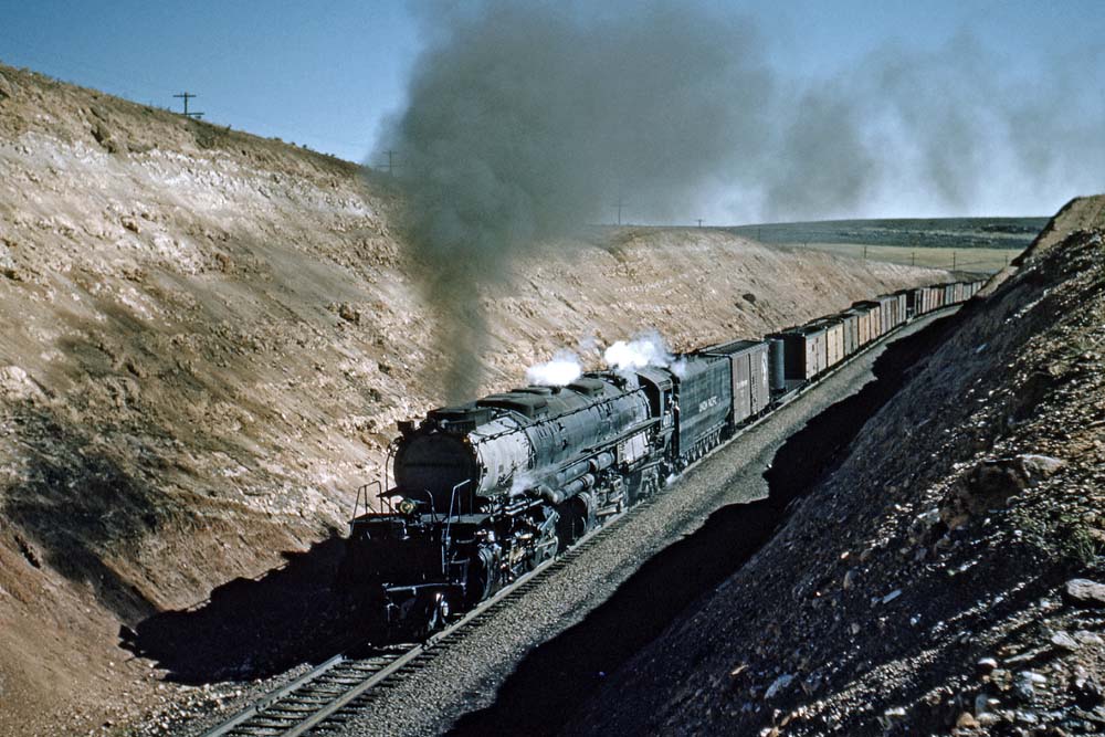 Smoking steam locomotive entering cut on curve