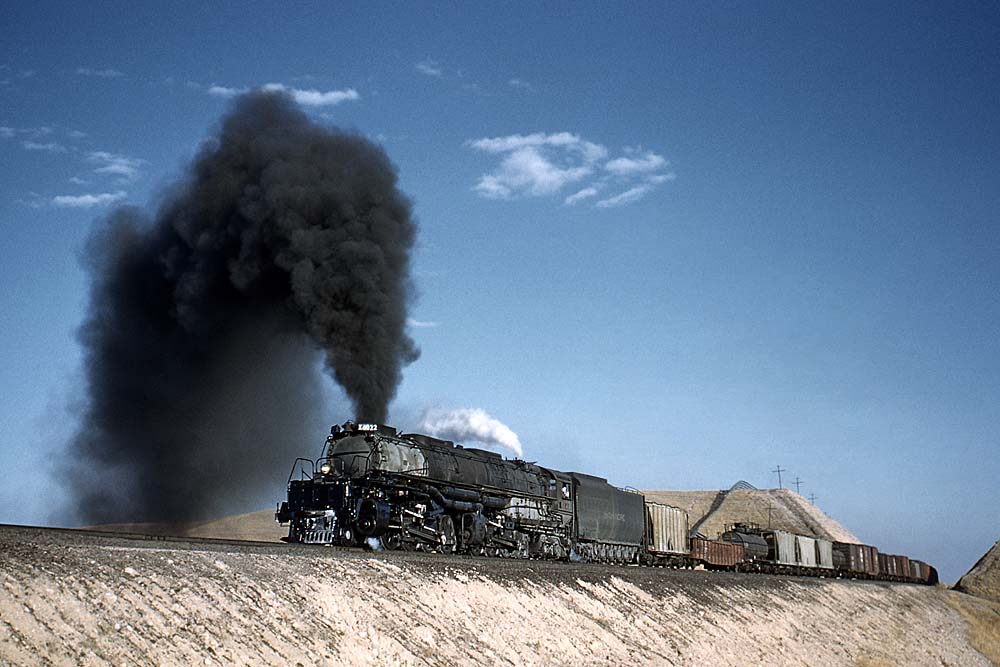 Steam locomotive smoking profusely cuts a profile against the sky