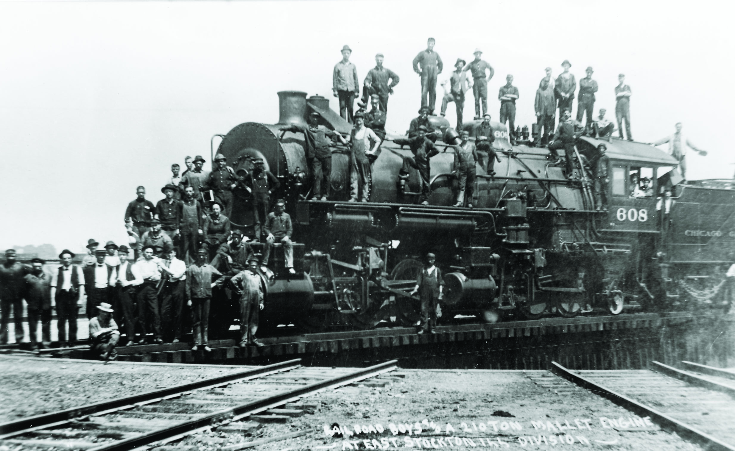 Men standing on and near steam locomotive spotted on turntable