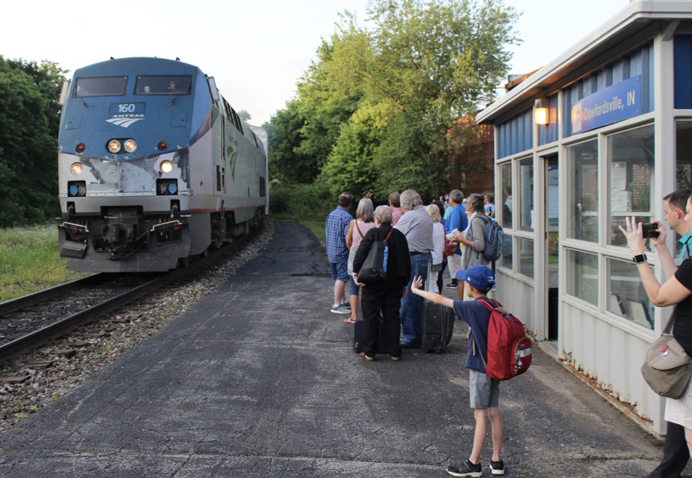 Passenger train arrives at station where people are waiting