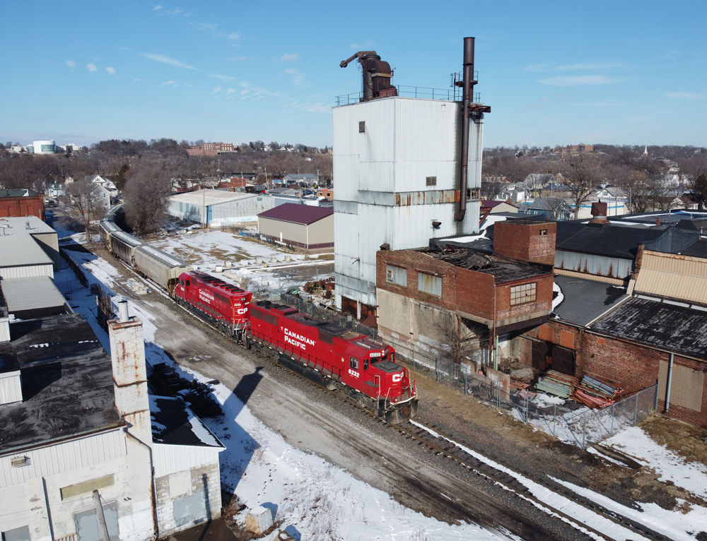 Train with red locomotives passing through industrial area.