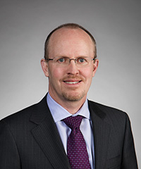 Head shot of man in suit and tie with glasses