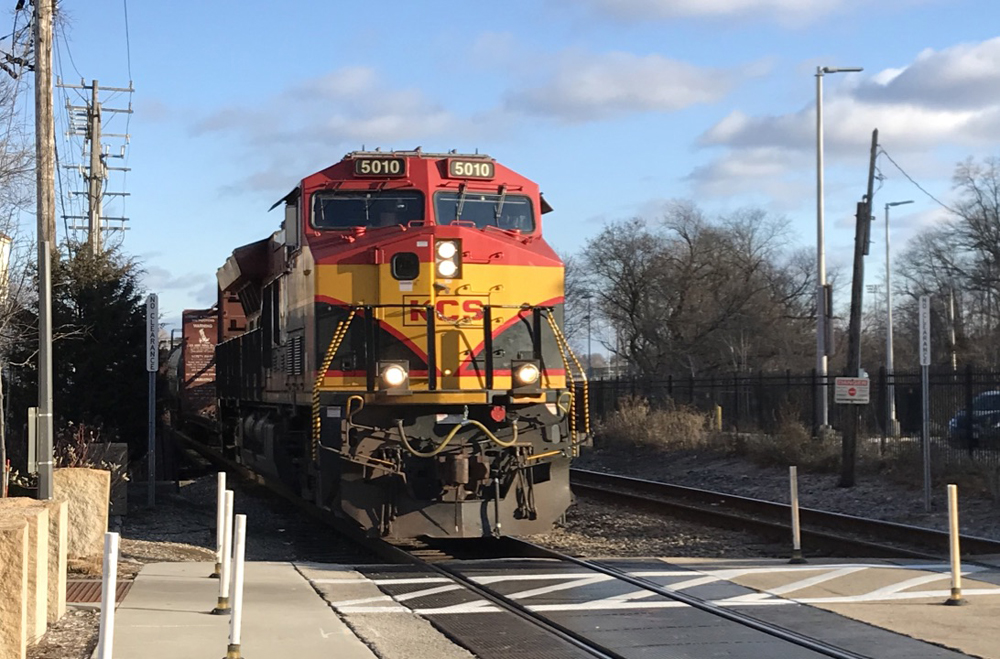 Red, yellow, and black locomotive at grade crossing