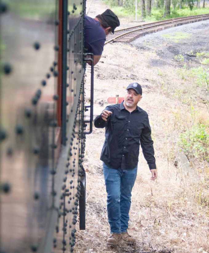 Man next to train talking to engineer