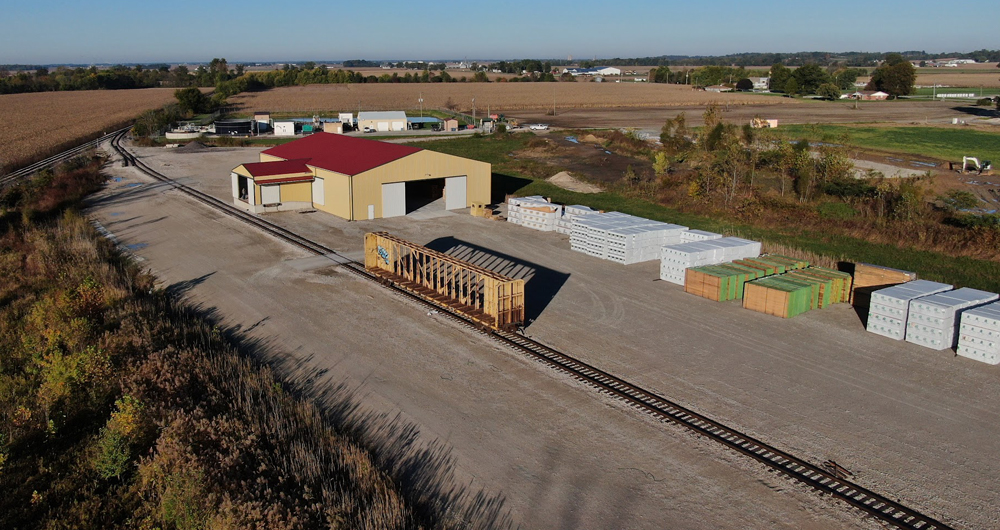 Drone photo of centerbeam flatcar on siding near warehouse