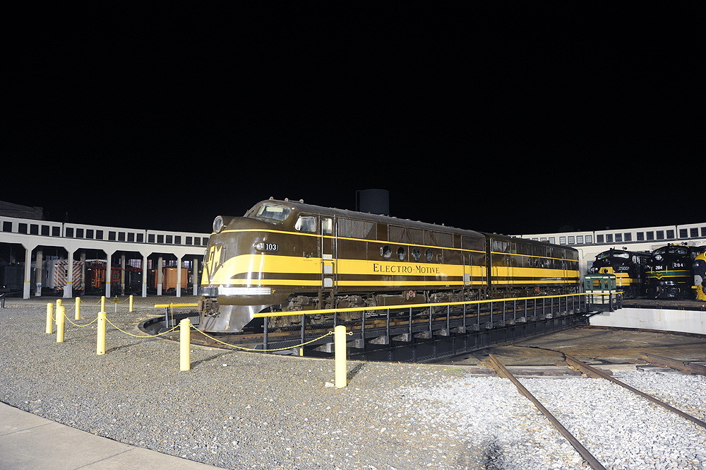 Brown and yellow locomotive on a turntable at night.