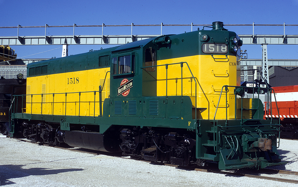 A green and yellow painted diesel locomotive under a clear sky.