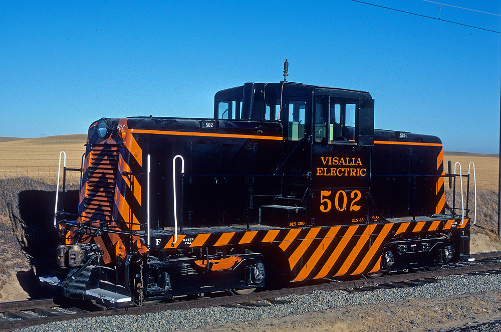 A black and orange-stripped center cab diesel locomotive.