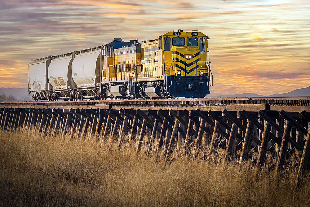 Train with two locomotives on low wooden bridge