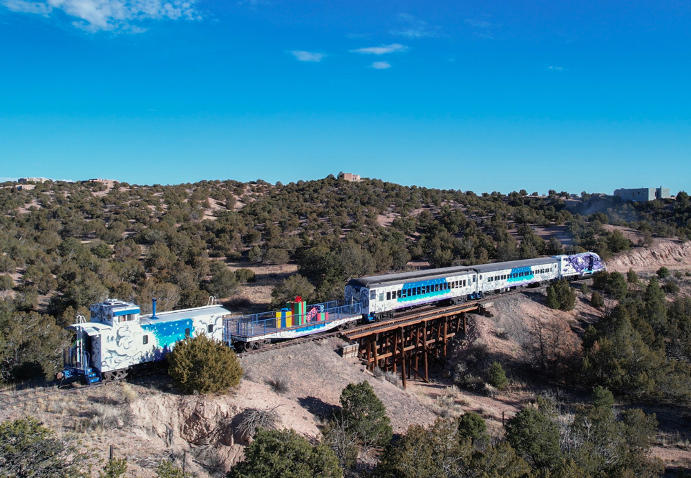Train with elaborate paint scheme and flatcar with giant Christmas packages in desert scenery
