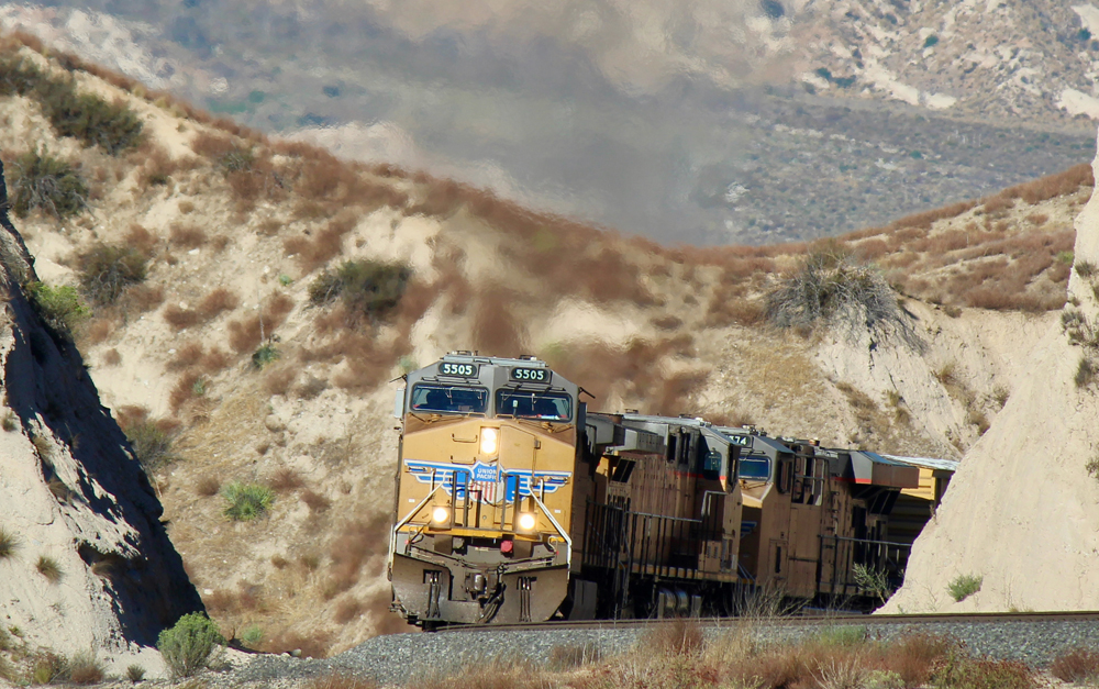 Train with yellow locomotives, with visible exhaust
