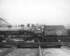 Steam locomotive stands on transfer table between buildings