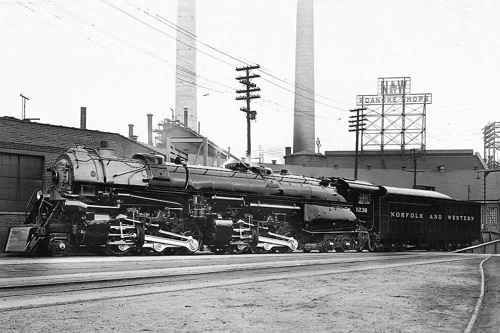 Articulated steam locomotive in front of factory building and smokestacks
