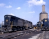 Blue diesel locomotives stand in front of concrete coaling tower