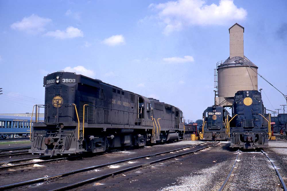 Blue diesel locomotives stand in front of a concrete coal tower