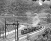 Steam locomotive reverses with short train on curve in valley
