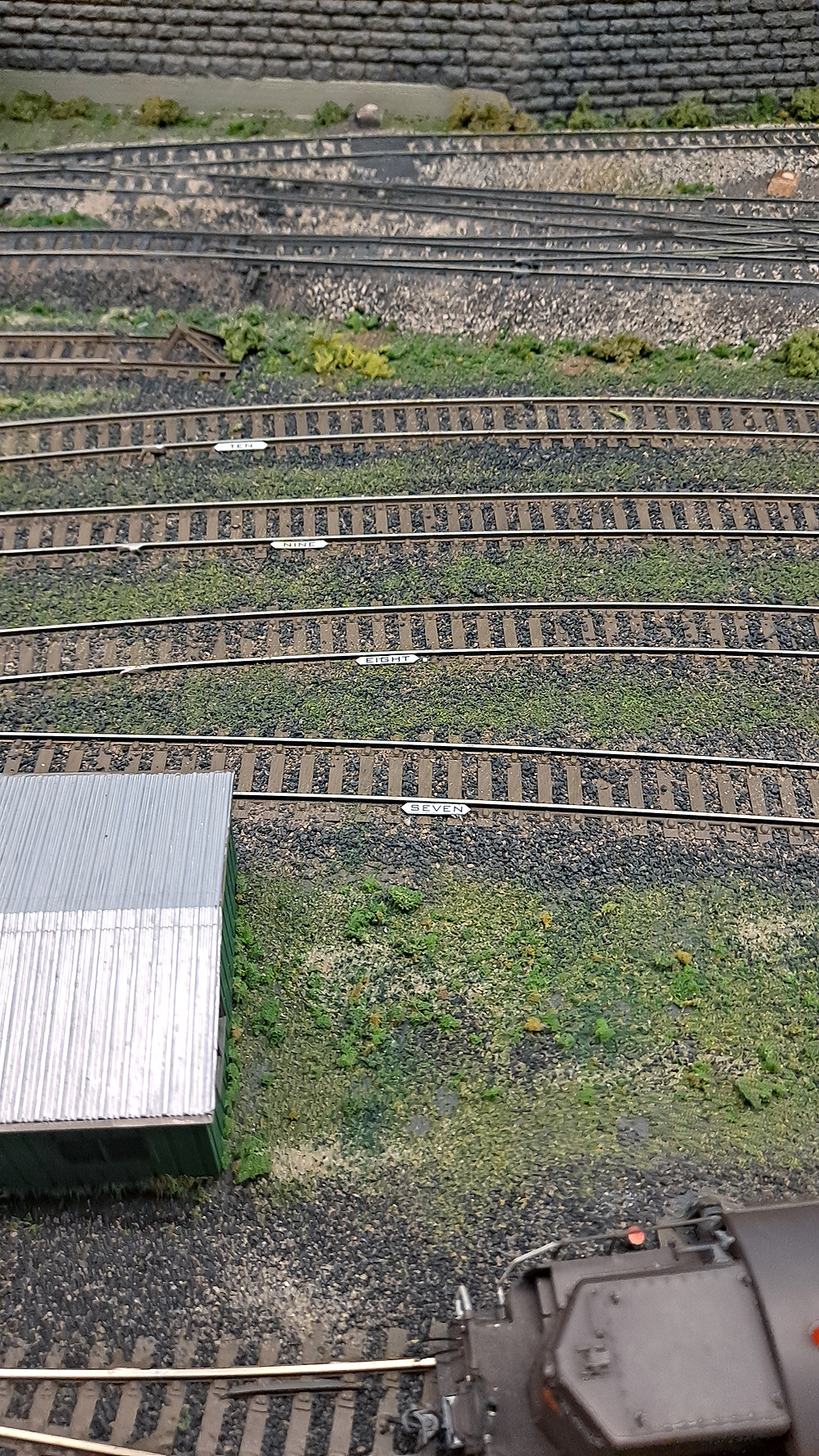 White pieces of styrene laid against the web of the track identify track numbers in a railroad yard.