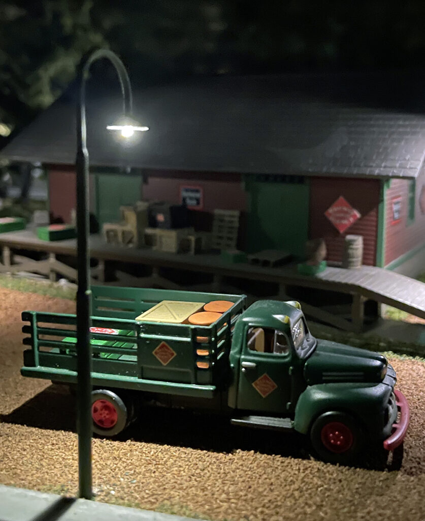 Swan neck lamp in front of a store and truck.