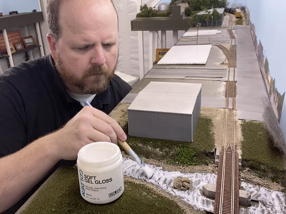 Man applying resin to model river
