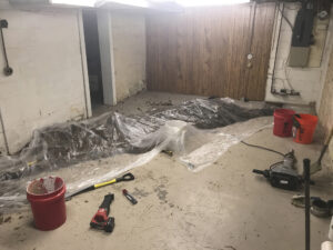A damaged basement with plastic sheeting and bucket
