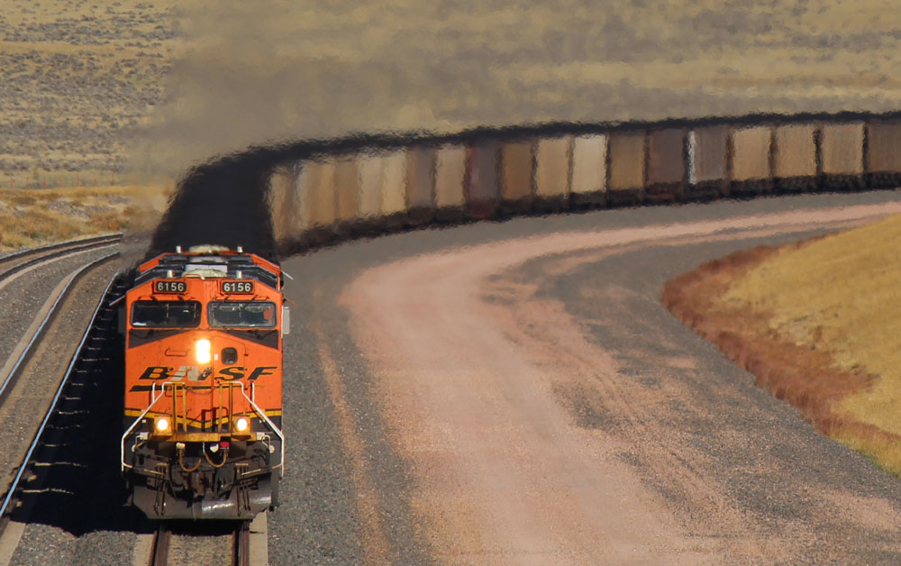 orange locomotive and train comes around curve in Wyoming