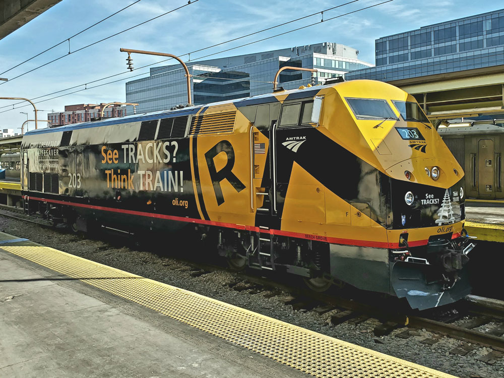 Alt text yellow and black locomotive on tracks near station