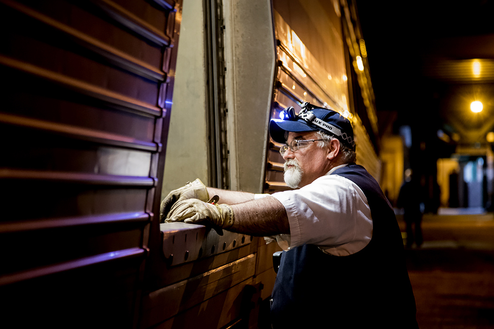 Man with gloves at door of baggate car at night