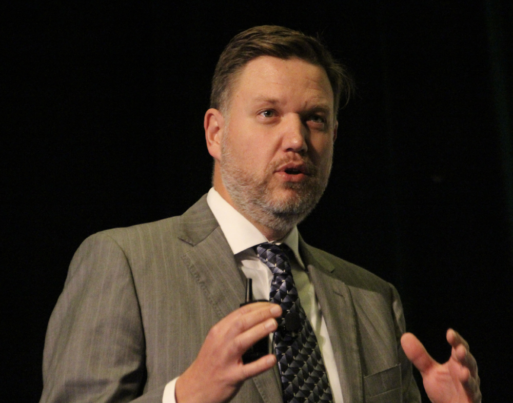 Man in brown suit gesturing