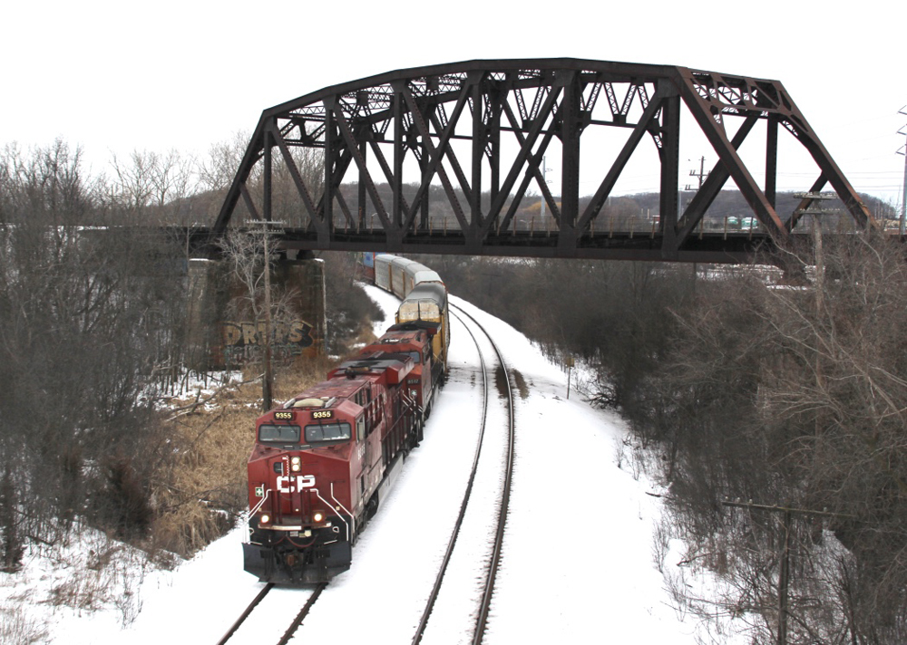 Train with red locomotives passes under bridge