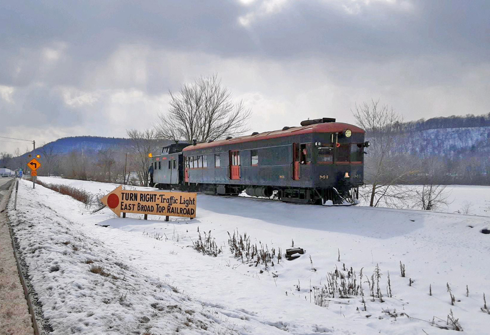 Gas-electric car pulling caboose in snow