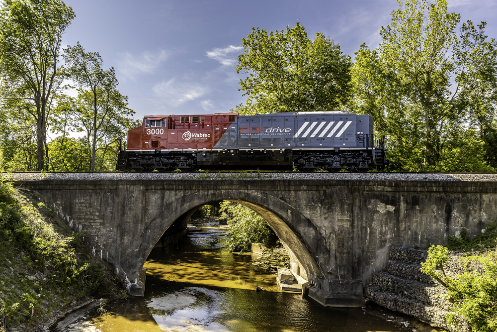 Gray and red locomotive on bridge