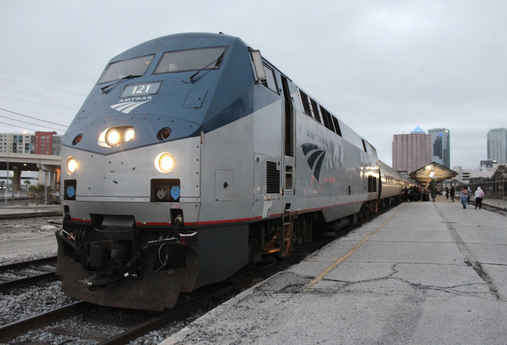 Passenger train with blue and silver locomotive at dusk