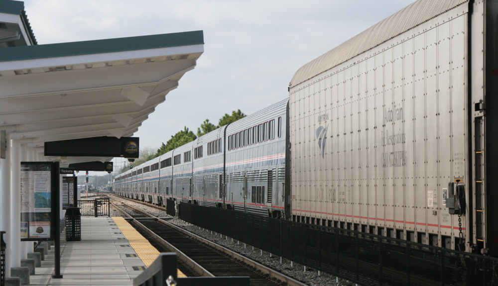 Long string of bilevel passenger cars ahead of auto racks