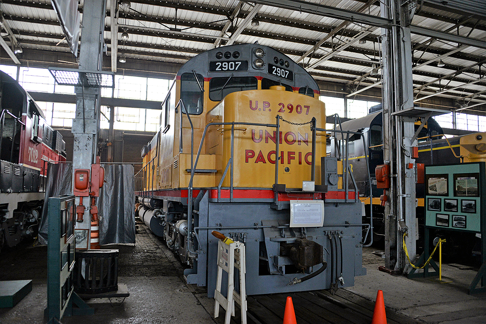 Yellow locomotive at rest in a large engine workshop.