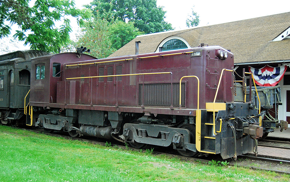 Maroon end-cab locomotive with yellow trim.