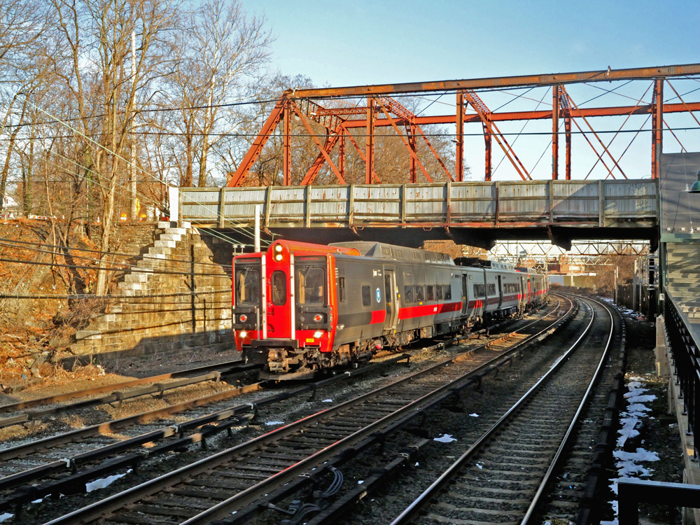 Commuter train passes under steel bridge
