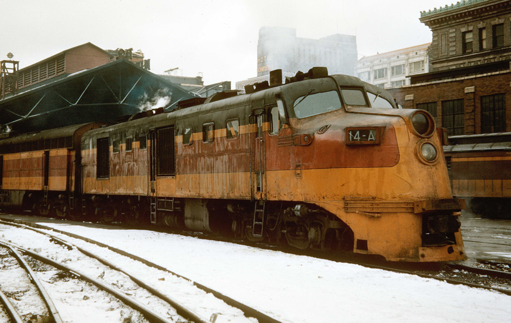 Orange, red, and black streamlined locomotive at station.