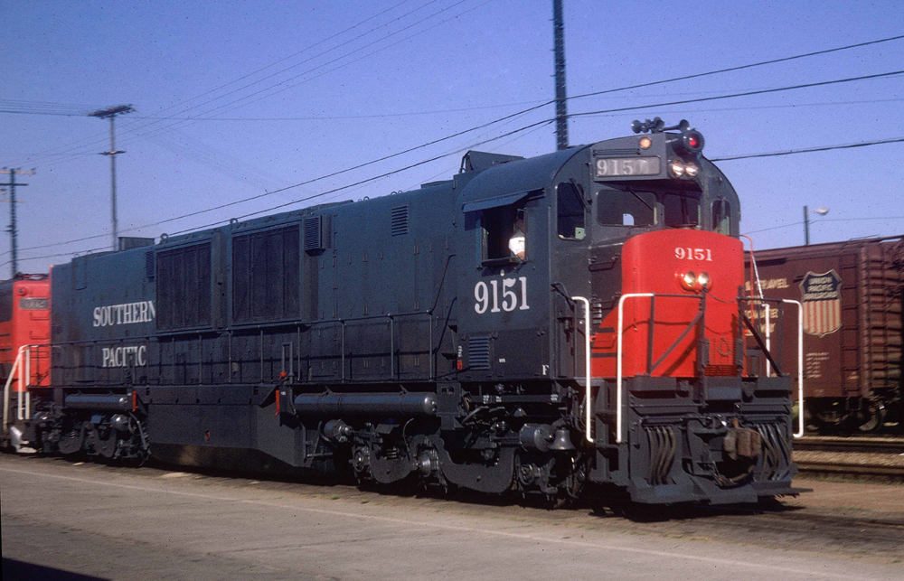 Gray and red locomotive with large radiators in mid-unit and two three-axle trucks.
