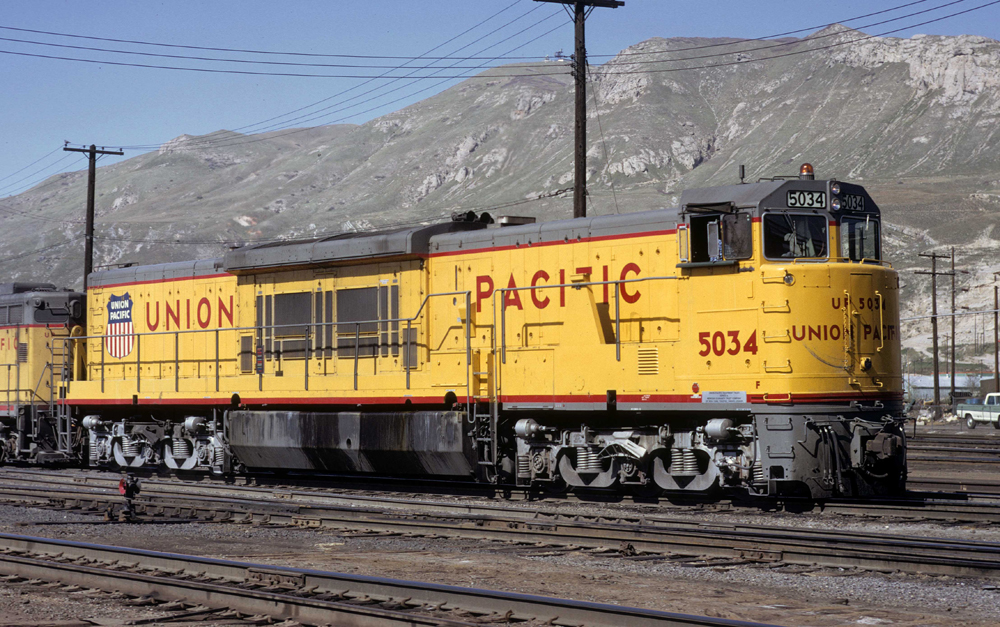 Yellow, gray, and red locomotive with short nose and six axles.