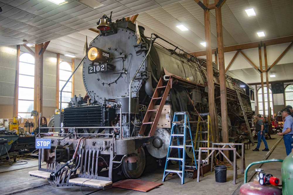 Three-quarters view of steam locomotive in shop building