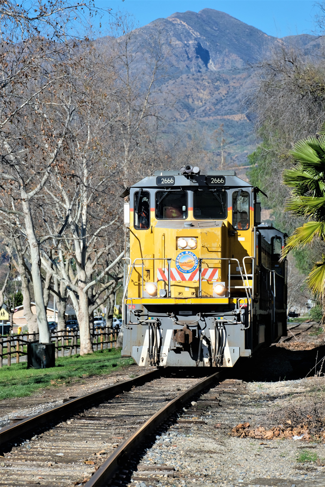 Yellow locomotives with hills in background