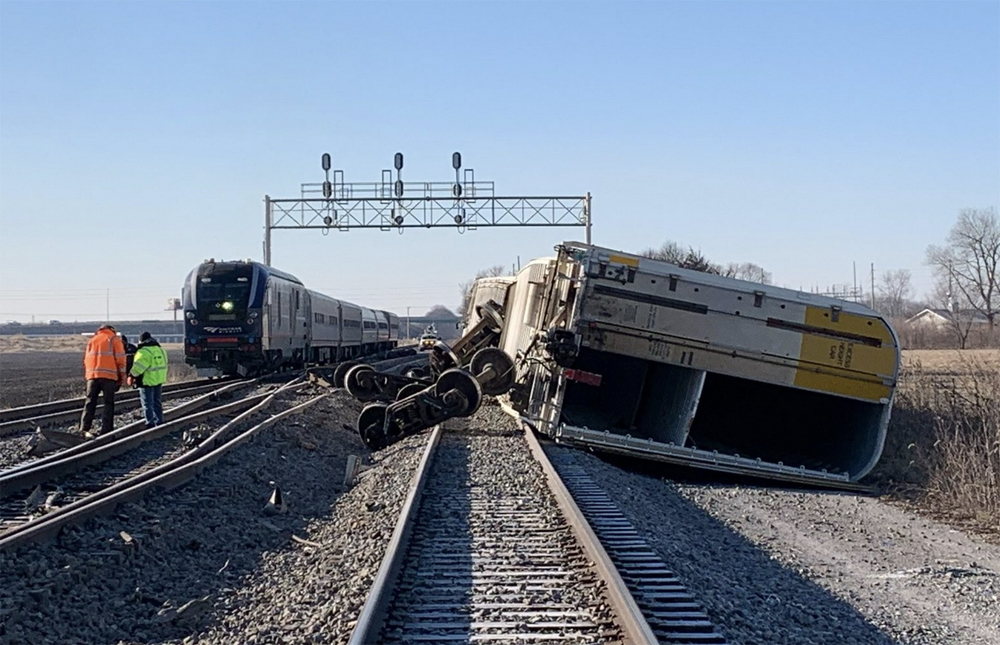 Passenger train stopped on track adjacent to derailed freight cars