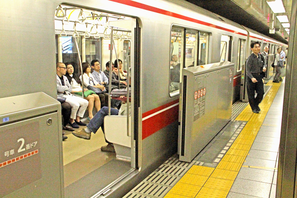 Barricades along edge of subway platform, with train in station